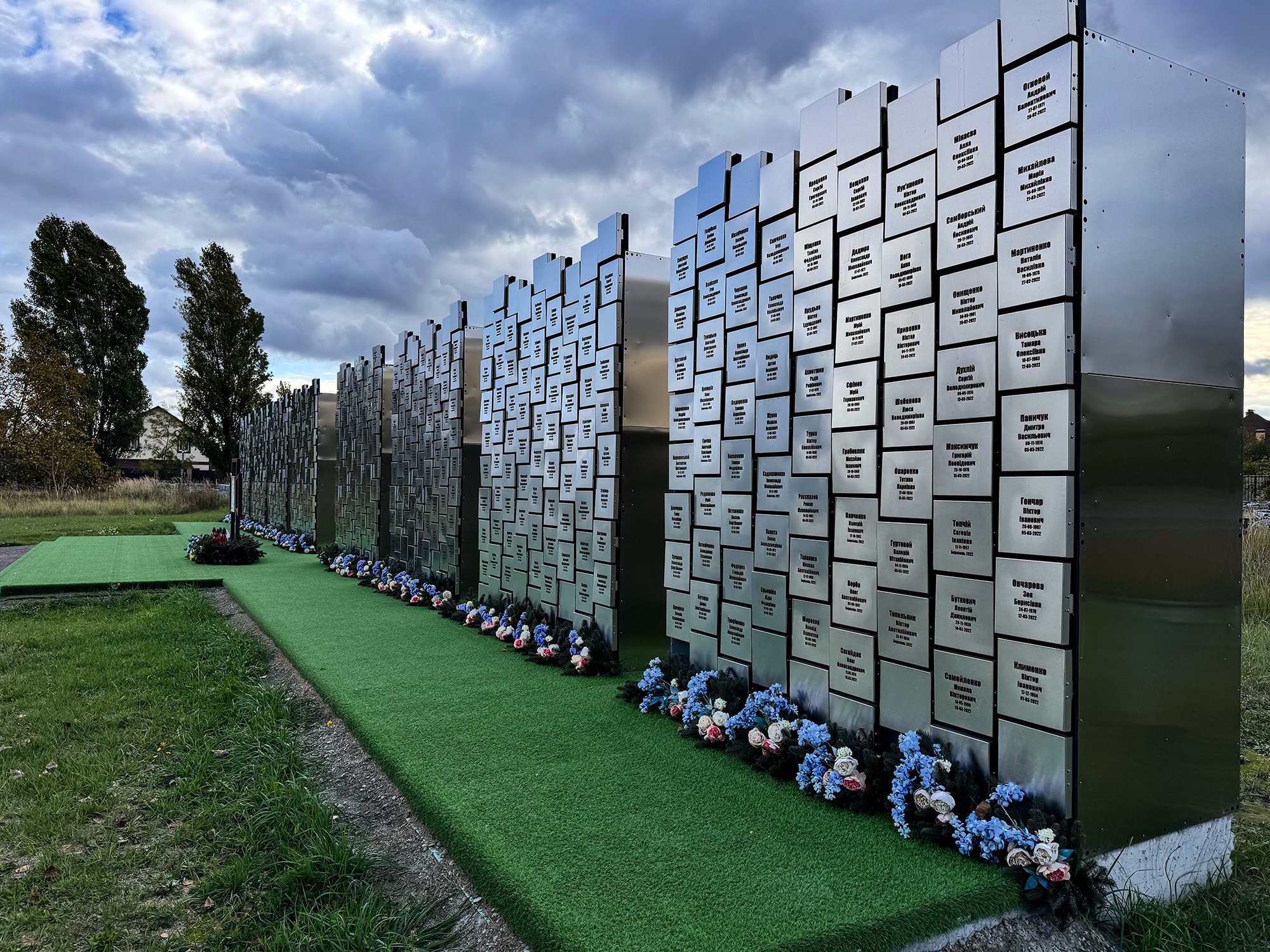 Oficiální památník masakru v Buči. Kde je zelený "koberec" byla před lety vyhloubená jáma, do které Rusové házeli Ukrajince, které zabili. Někteří měli svázané ruce. 
Autor: Erik Tabery