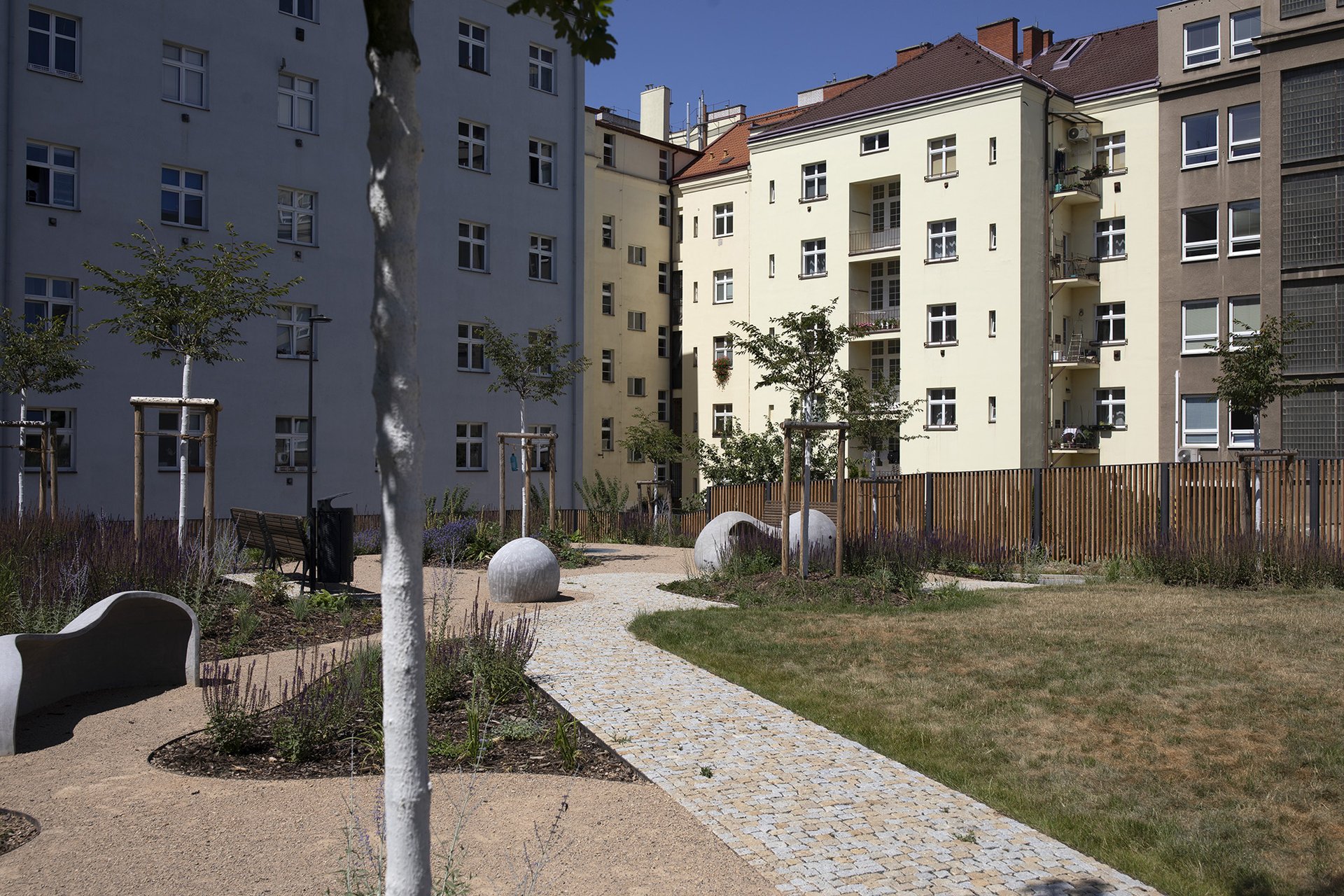 Stín a ochlazení v rozpáleném městě. (Zrekonstruovaný veřejně přístupný vnitroblok v ulici U Uranie v pražských Holešovicích s prvky modrozelené infrastruktury včetně čtrnácti nově vysazených stromů)
Autor: Milan Bureš