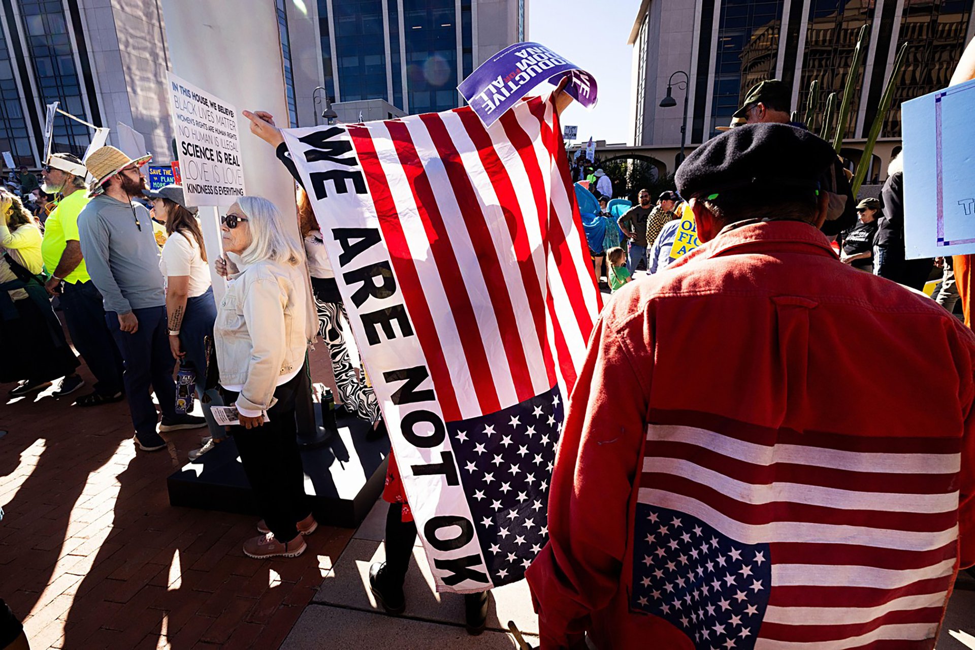 Protesters hold “No Kings” signs during a political demonstration in downtown Tucson, Arizona, on October 18, 2025.