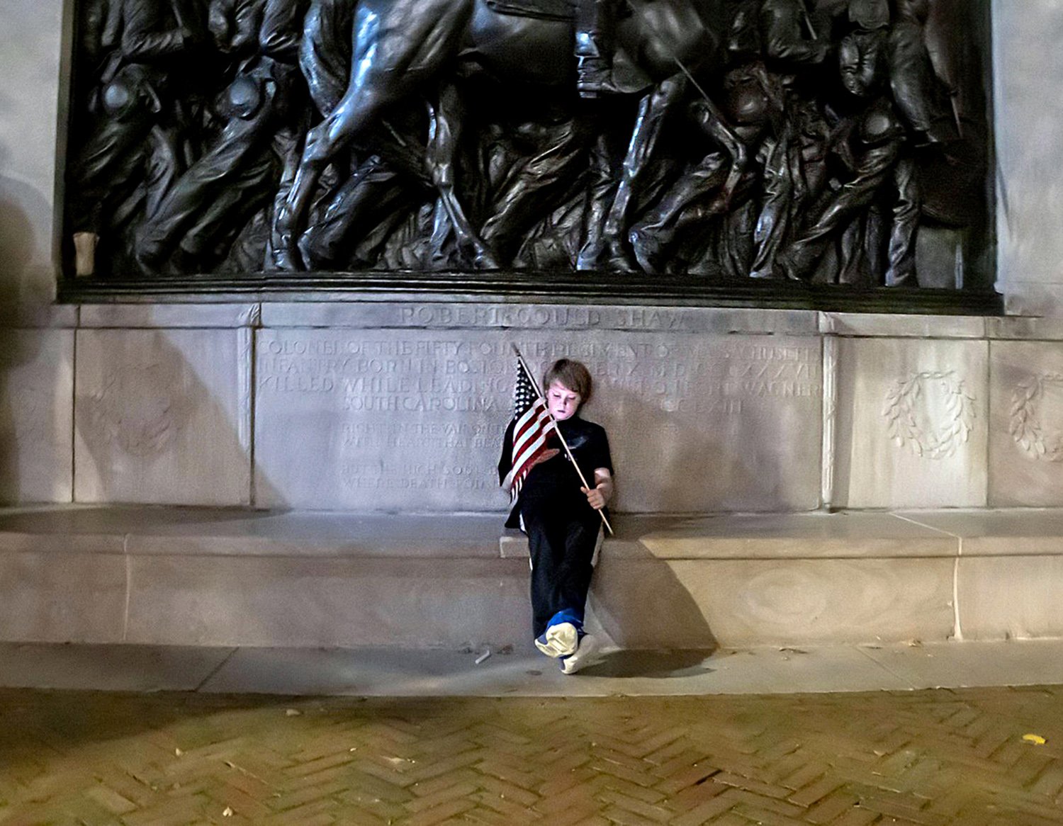 September 18, 2025  Boston, Massachusetts, USA A child holding an American flag in front the Saint-. Gaudens memorial of to the 54th Regiment from the Civil War as  hundreds of people gathered outside the Massachusetts State House Thursday evening, Septem
