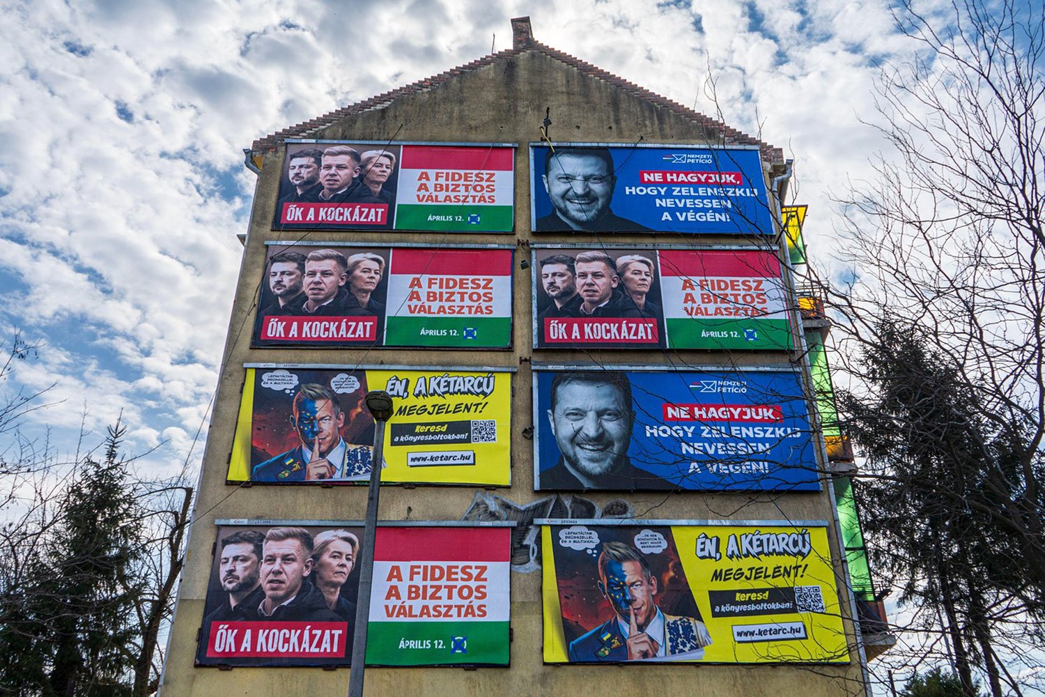 Apartment building facade covered with Fidesz campaign posters featuring Péter Magyar and Volodymyr Zelenskyy during Hungary’s 2026 election campaign.