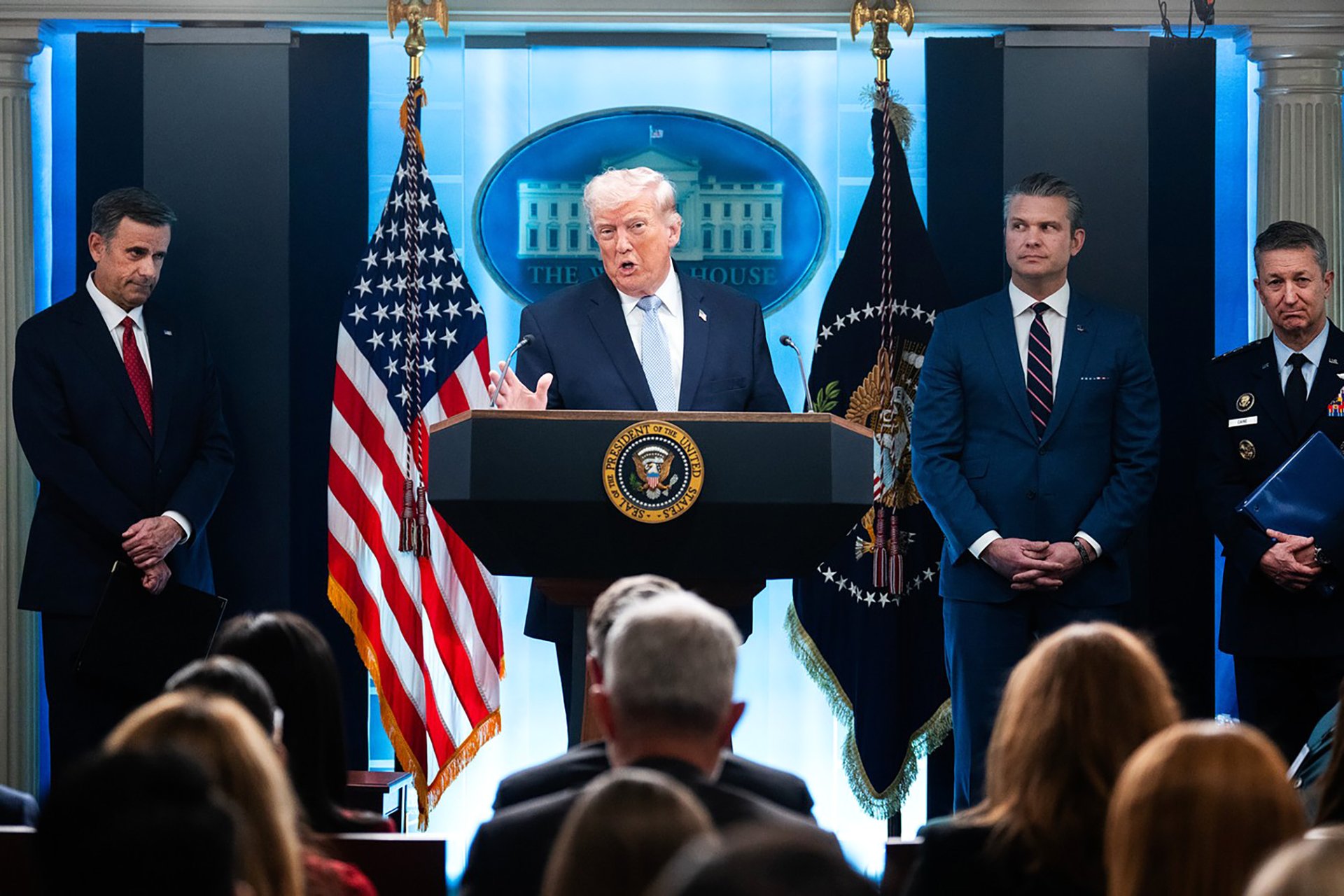 Prezident Donald Trump, ředitel CIA John Ratcliffe (vlevo), ministr obrany Pete Hegseth a předseda Sboru náčelníků štábů Dan Caine vedou v pondělí 6. dubna 2026 tiskovou konferenci v zasedací místnosti Bílého domu o válce v Íránu.